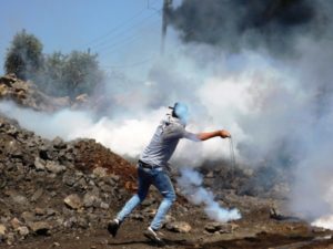 un ragazzo rilancia un lacrimogeno