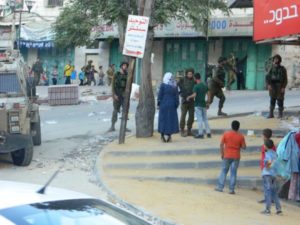 A un uomo e una donna palestinese viene negato l'ingresso attraversando la strada, mentre coloni israeliani sono accompagnati nel loro tour. 